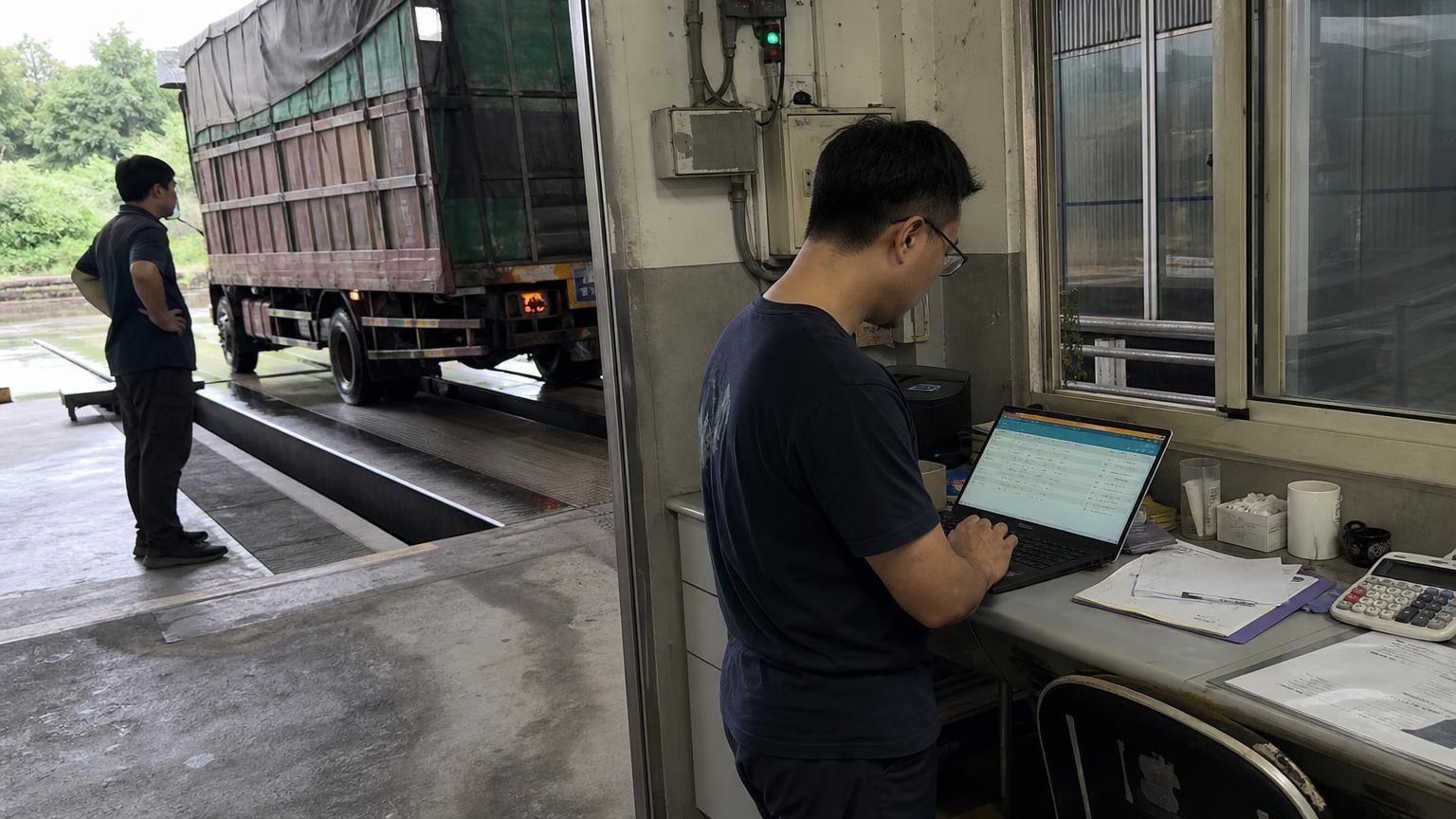臺灣企業在地磅作業現場使用電腦處理自動化流程的情境照
